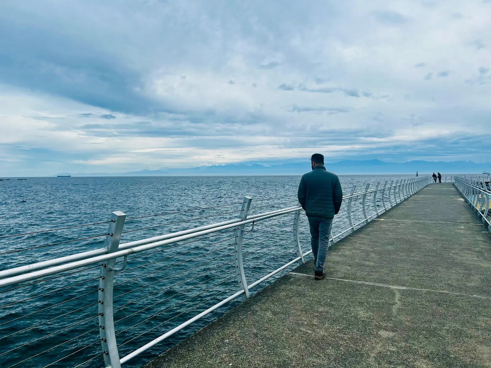Salman Haider walking on a pier beside the ocean