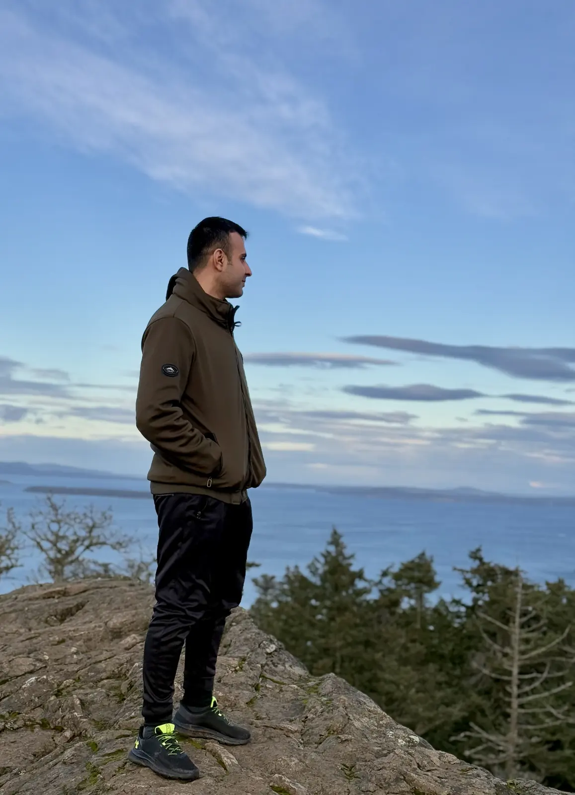 Salman Haider standing on a rocky viewpoint with the ocean behind him